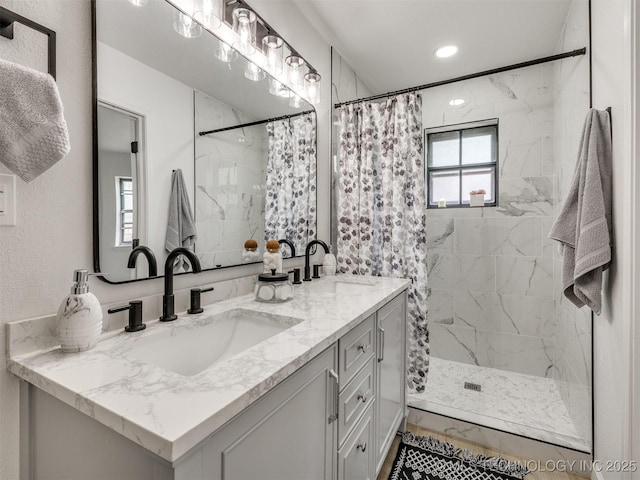 full bath featuring double vanity, a stall shower, marble finish floor, and a sink