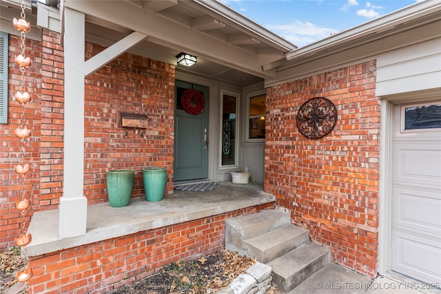 view of exterior entry with brick siding and an attached garage