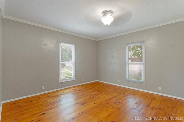 unfurnished room featuring a textured wall, ornamental molding, wood finished floors, and baseboards