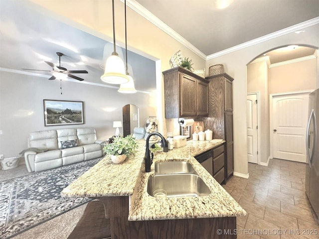 kitchen featuring arched walkways, light stone counters, a sink, and decorative light fixtures