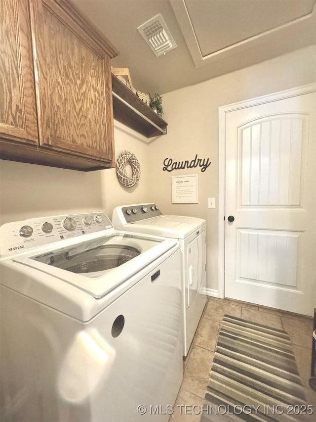 clothes washing area with visible vents, cabinet space, washing machine and clothes dryer, and light tile patterned floors