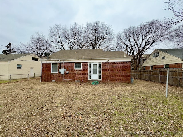 back of property with crawl space, a yard, a fenced backyard, and brick siding