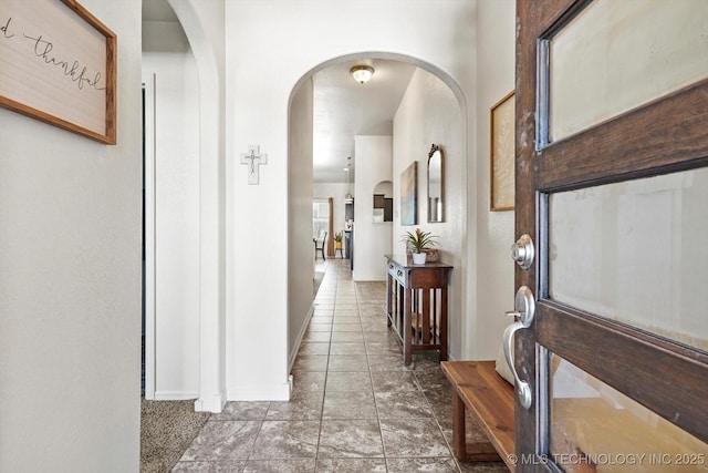 foyer entrance featuring arched walkways and baseboards