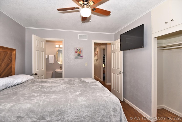 bedroom featuring baseboards, visible vents, dark wood-style floors, a textured ceiling, and crown molding