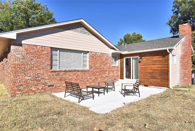 rear view of house featuring brick siding, a yard, a patio, a chimney, and crawl space