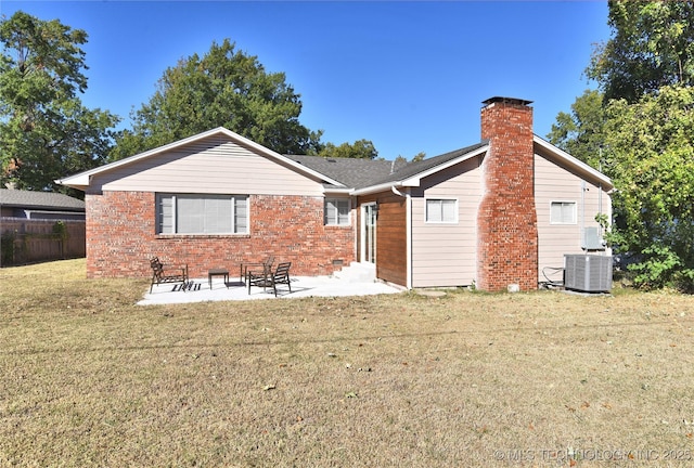 back of property featuring brick siding, a yard, a chimney, a patio area, and fence