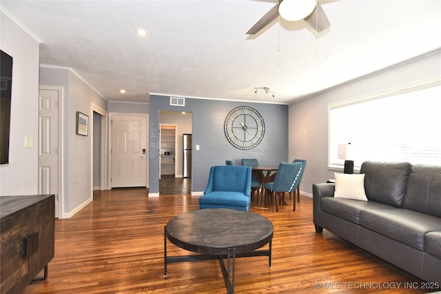 living room with dark wood-style floors, crown molding, visible vents, a ceiling fan, and baseboards