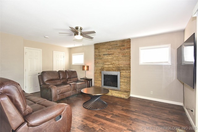 living room with a fireplace, dark wood finished floors, baseboards, and ceiling fan