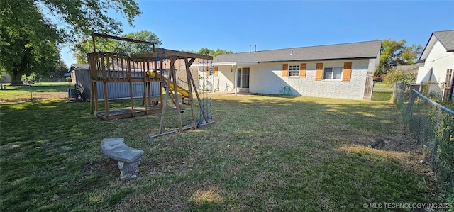 exterior space featuring brick siding, a fenced backyard, a playground, and a yard