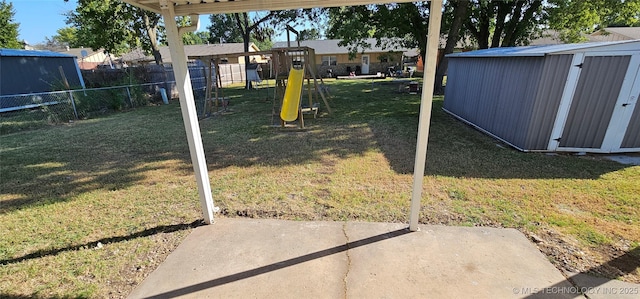 view of yard featuring a playground, a patio, a storage unit, fence, and an outdoor structure