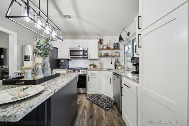 kitchen with a sink, white cabinetry, appliances with stainless steel finishes, open shelves, and pendant lighting