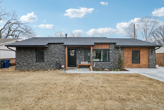 view of front facade featuring stone siding, a shingled roof, and a front yard