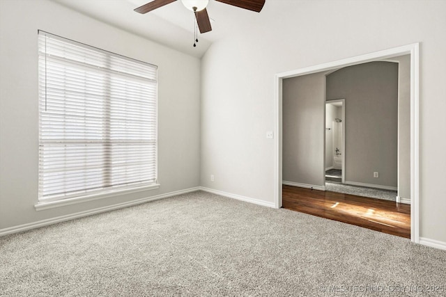 carpeted empty room featuring vaulted ceiling, ceiling fan, and baseboards