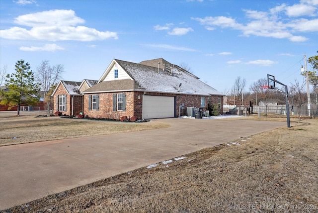 view of front of home featuring driveway, brick siding, an attached garage, fence, and a front yard