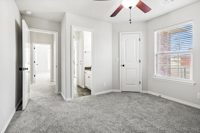 unfurnished bedroom with visible vents, ensuite bathroom, a ceiling fan, light carpet, and baseboards