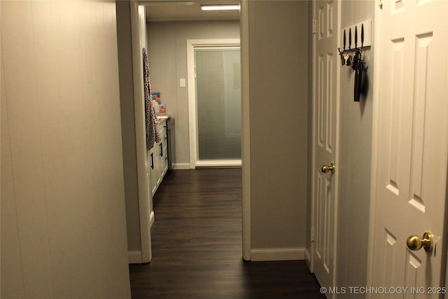 corridor featuring dark wood-style flooring and baseboards