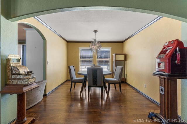 dining area featuring dark wood-style floors, a chandelier, and crown molding