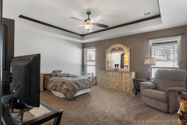 carpeted bedroom featuring visible vents, ornamental molding, a raised ceiling, and a ceiling fan