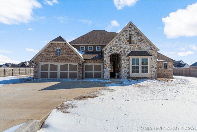 view of front facade with driveway, an attached garage, fence, and brick siding