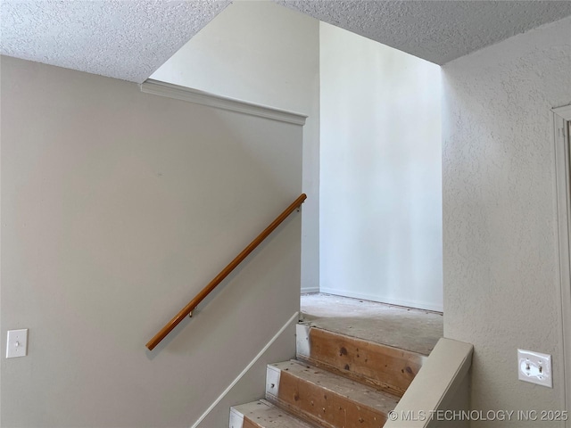 staircase with a textured wall and a textured ceiling