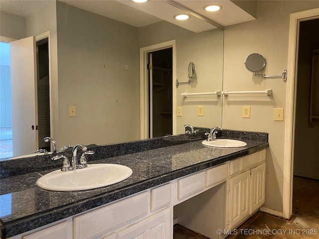 full bathroom with double vanity, baseboards, a sink, and recessed lighting