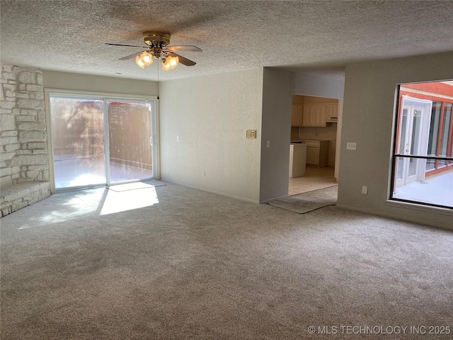 empty room featuring a textured ceiling, washer / clothes dryer, a ceiling fan, and light colored carpet