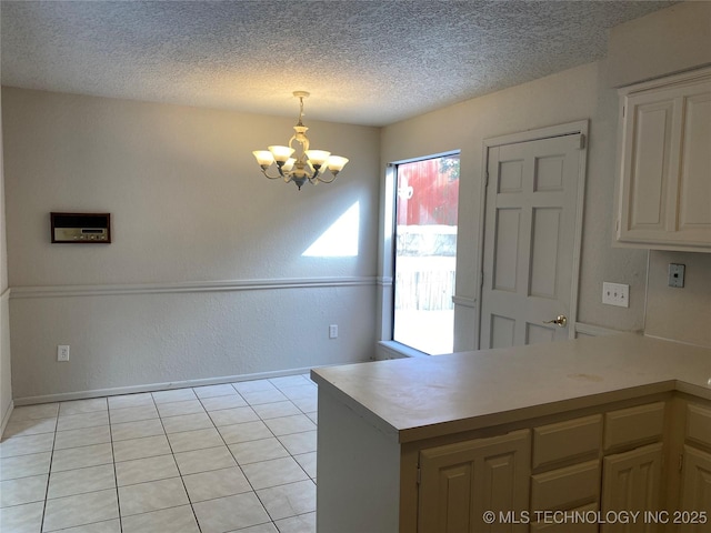 interior space featuring a textured wall, light tile patterned flooring, a notable chandelier, and a textured ceiling