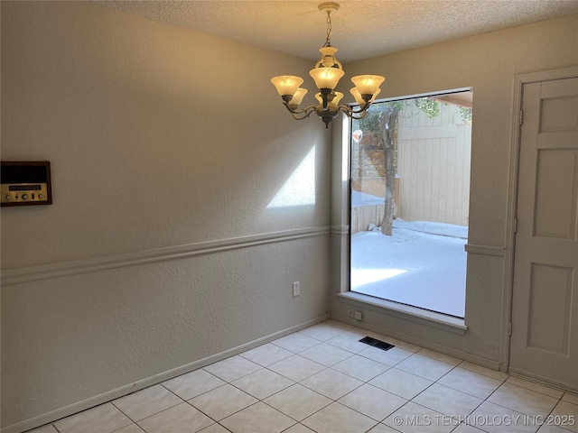 unfurnished room featuring a chandelier, a textured wall, a textured ceiling, visible vents, and baseboards