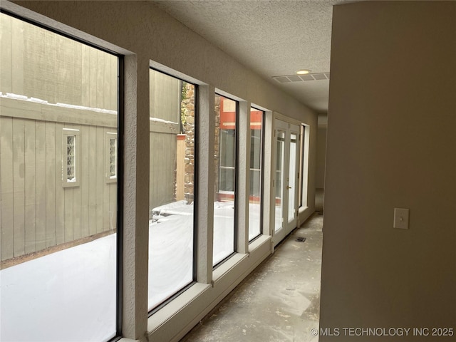 hallway featuring a textured ceiling, unfinished concrete flooring, and visible vents