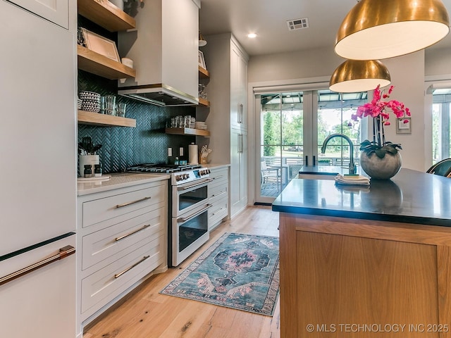 kitchen featuring visible vents, white refrigerator, double oven range, open shelves, and a sink