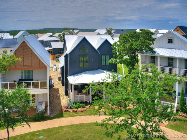 back of house featuring a standing seam roof, a residential view, and metal roof