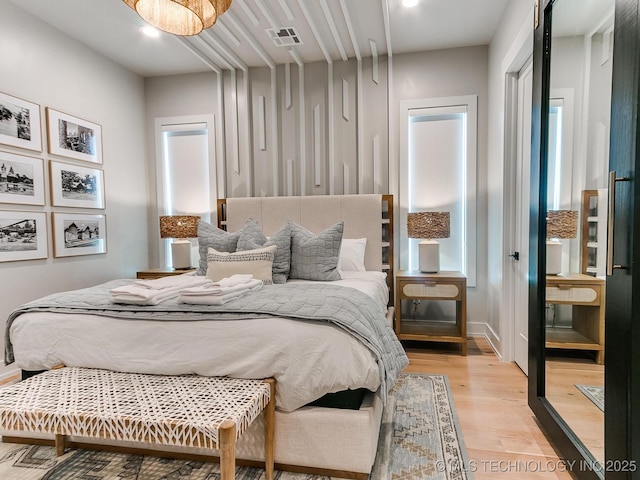 bedroom with light wood-style floors and visible vents