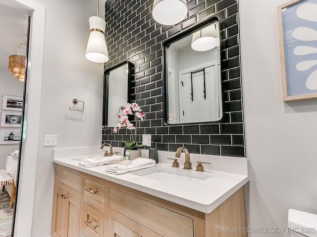 bathroom with a sink, backsplash, ensuite bathroom, and double vanity