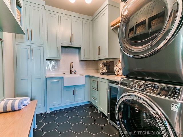 laundry area with wine cooler, stacked washer / dryer, a sink, and cabinet space