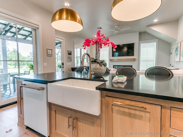 kitchen with a sink, visible vents, open floor plan, dishwasher, and dark countertops