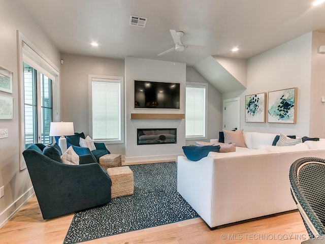 living room with light wood-style floors, recessed lighting, visible vents, and a glass covered fireplace