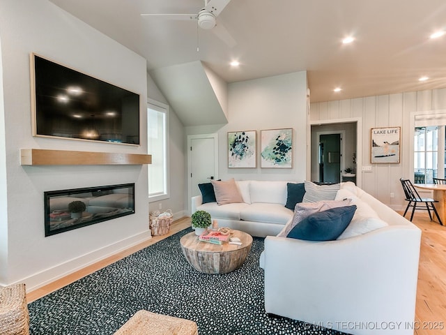 living room featuring recessed lighting, wood finished floors, a ceiling fan, baseboards, and a glass covered fireplace