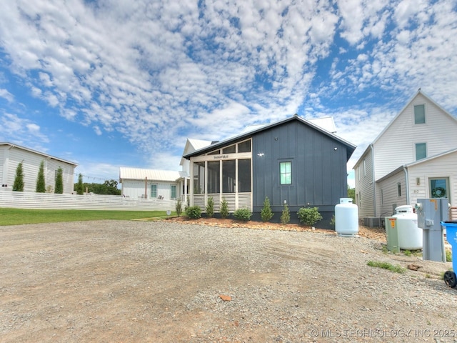 exterior space featuring board and batten siding, a sunroom, and fence