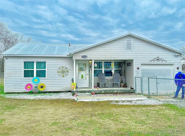 view of front of home with metal roof, a front lawn, an attached garage, and fence