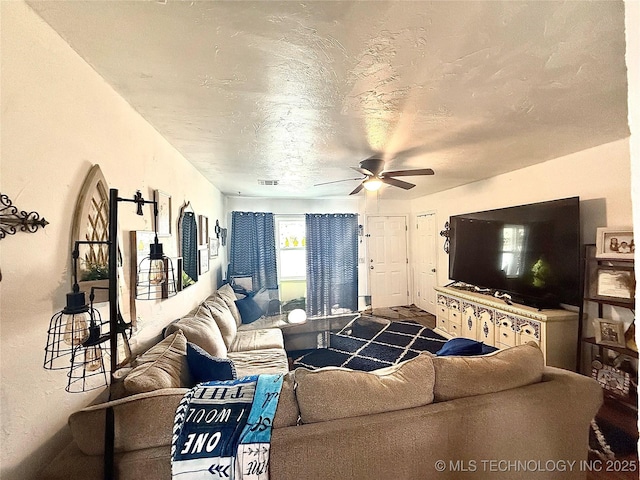 living room with ceiling fan, visible vents, and a textured ceiling