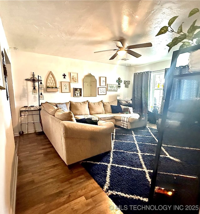 living room with ceiling fan, a textured ceiling, and wood finished floors