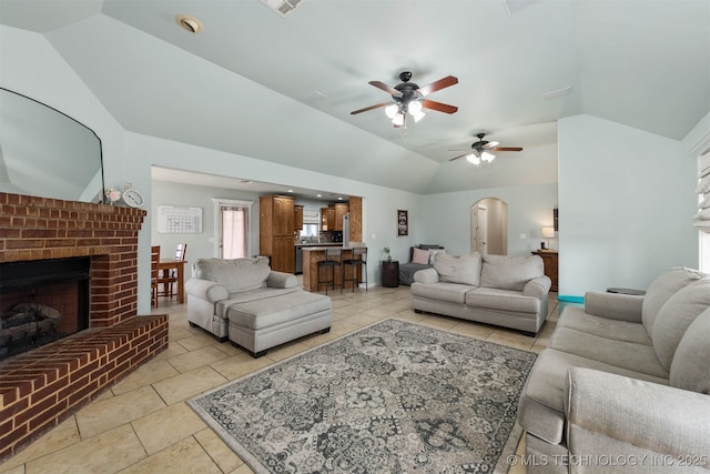 living room featuring lofted ceiling, light tile patterned floors, a fireplace, and arched walkways