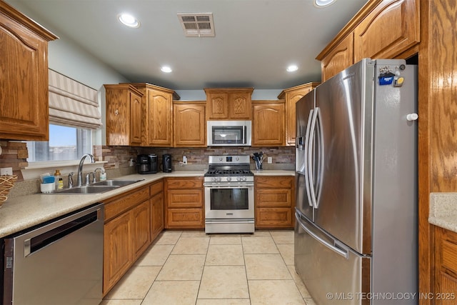 kitchen with visible vents, brown cabinetry, appliances with stainless steel finishes, light countertops, and a sink