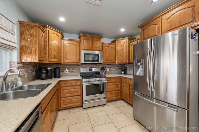 kitchen featuring visible vents, appliances with stainless steel finishes, a sink, light countertops, and backsplash