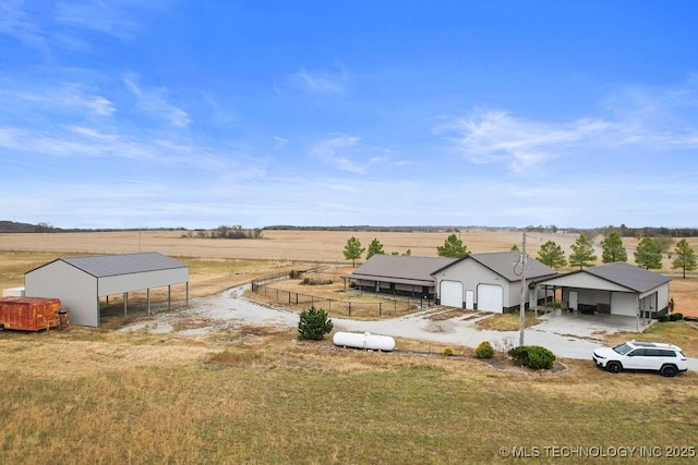 view of yard with driveway, a rural view, an attached garage, and fence