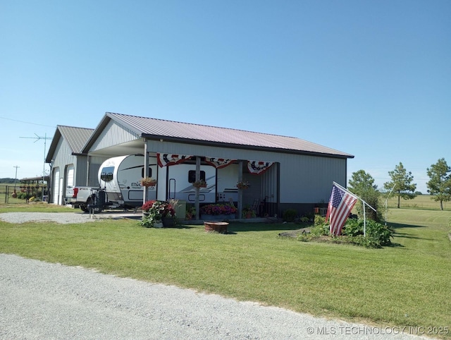 view of home's exterior featuring a carport, a detached garage, metal roof, and a lawn