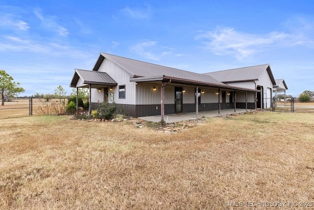 view of side of home with a yard, a gate, metal roof, and fence