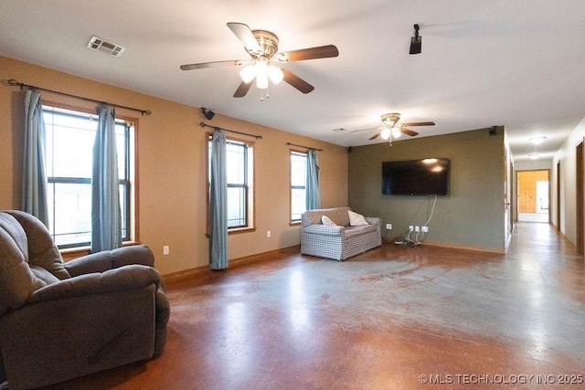 living area featuring baseboards, concrete floors, visible vents, and a ceiling fan