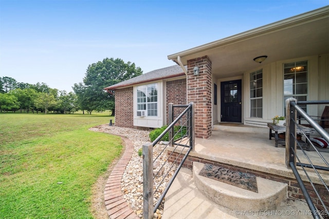 doorway to property featuring a yard and brick siding