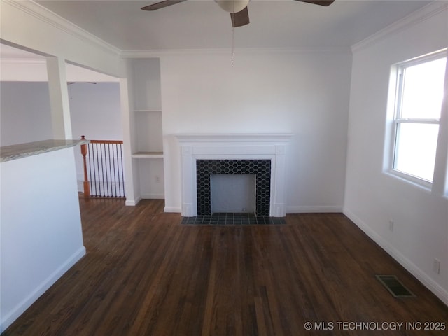 unfurnished living room with built in shelves, a tile fireplace, dark wood-type flooring, visible vents, and ornamental molding